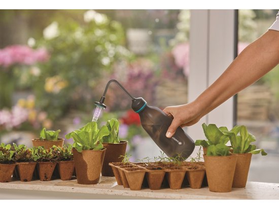 GARDENA plantenspuit met turquoise mondstuk, gevuld met water boven plantenbak