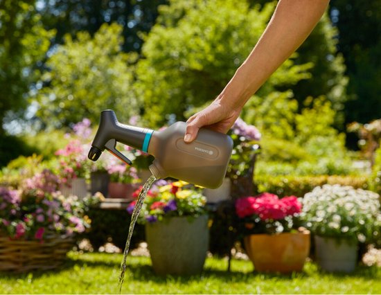 Gardena plantenspuit met blauwe band, sproeistraal op bloemen in de tuin
