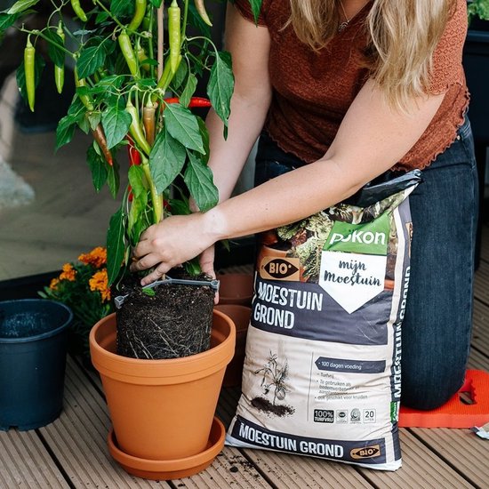 Pokon moestuingrondzak bij pot met donkere aarde, vastgehouden door een tuinier.