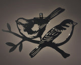Solar ijzeren vogel wanddecoratie met twee zwarte vogels; zonlicht glimt op het metaal