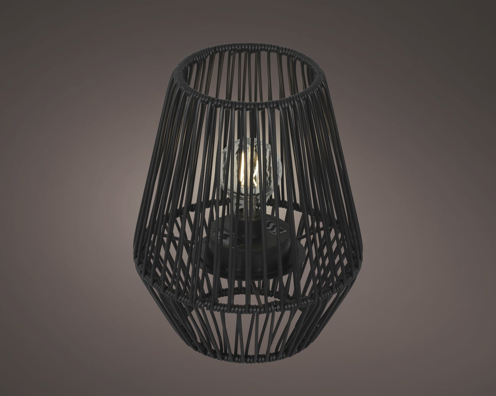 Solarlantaarn met zwarte rieten kooi en brandende kaarslamp, frontaal