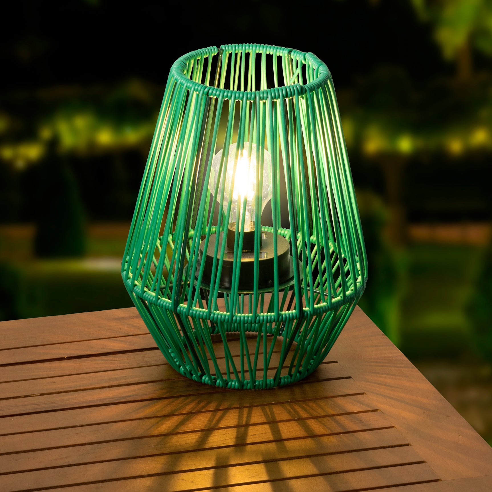 Groene rieten solar lantaarn met warm brandend licht door de kooi.