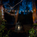 Hanglamp met zwarte rieten lampenkap en metalen ketting, warme lichtgloed zichtbaar