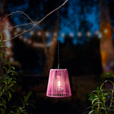 Roze hanglamp met gevlochten rieten kap, verlicht aan een ketting