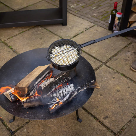 Popcornpan met gaasmandje op open vuur, met lange steel
