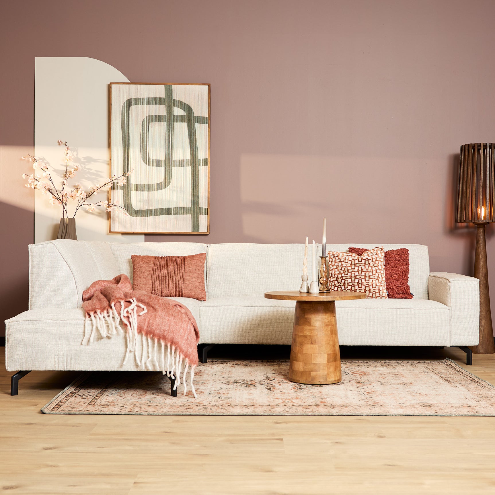 Beige divanbank met sierkussens en plaid, strakke bekleding en houten poten