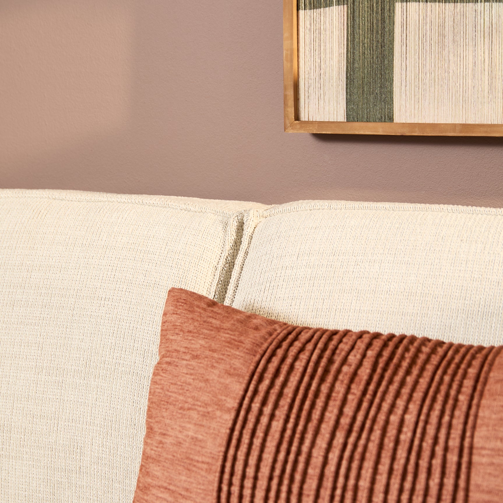 Beige bankzitting met grove stof, siernaad en rode sierkussenhoek