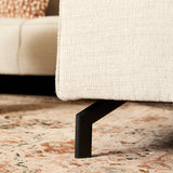 Beige divanbank met zwarte poot en afgeronde zoom, grove stoffen bekleding