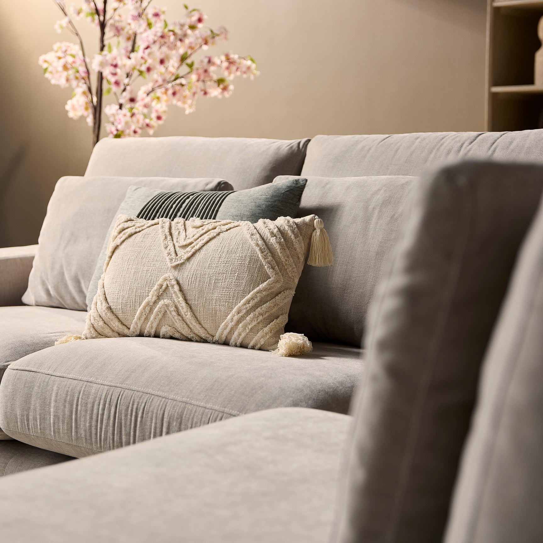 Beige bank met sierkussens en plaid, beige stof en ronde zitrand