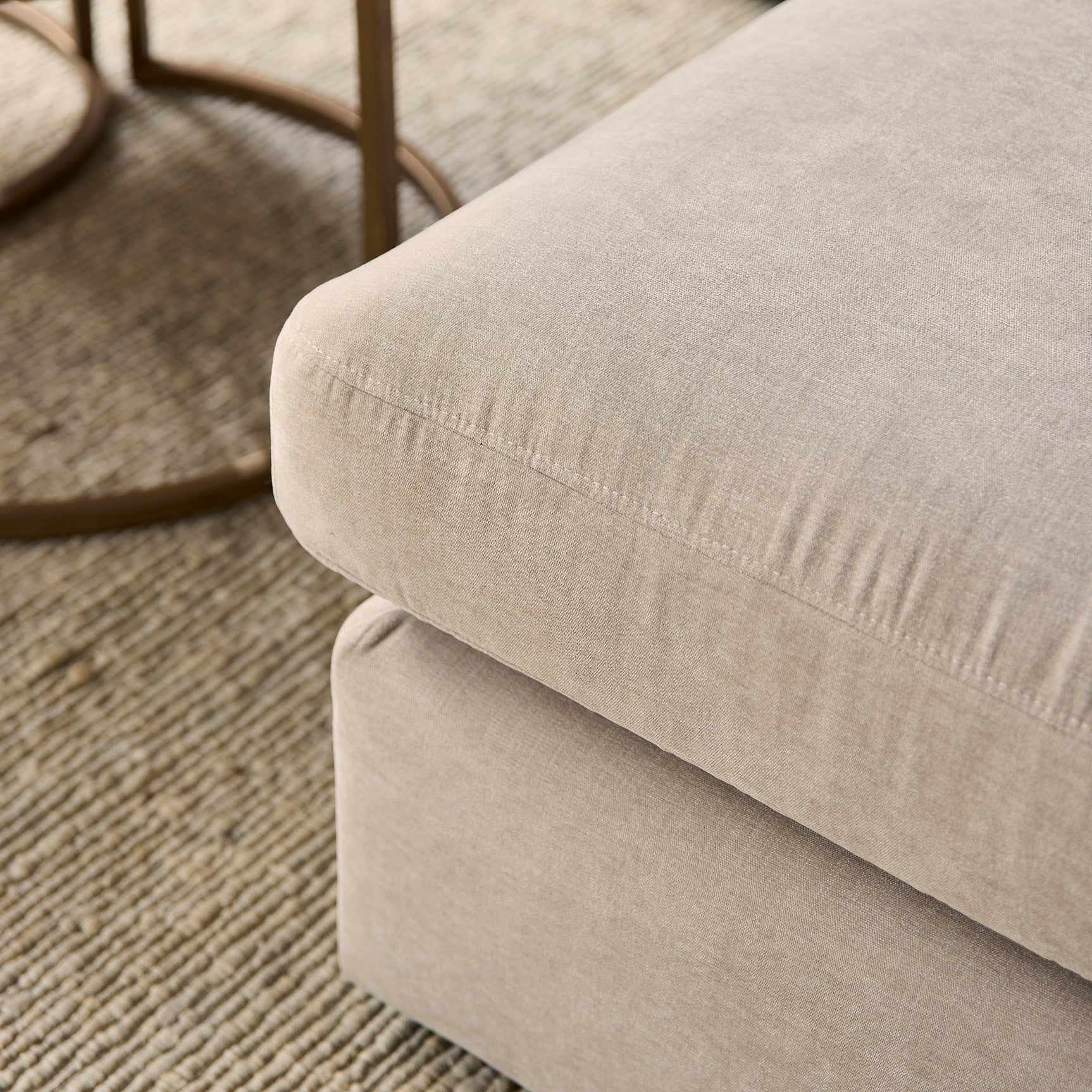 Beige bankarm en zitrand met zichtbare stiksels, textuur van de stof