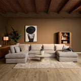 U-vormige bank in lichtbeige stof met lage rugkussens en chaise-arm