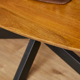 Ovale houten eettafel met zwart metalen pootkruis en bruintint blad, detail.