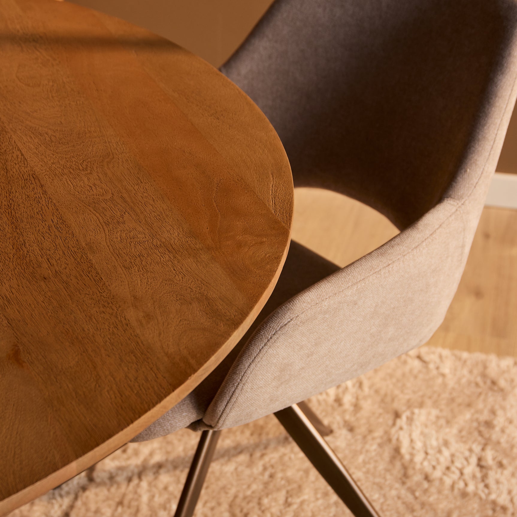 Close-up van naturel houten tafelblad en afgeronde rand met stoffen stoelzitting