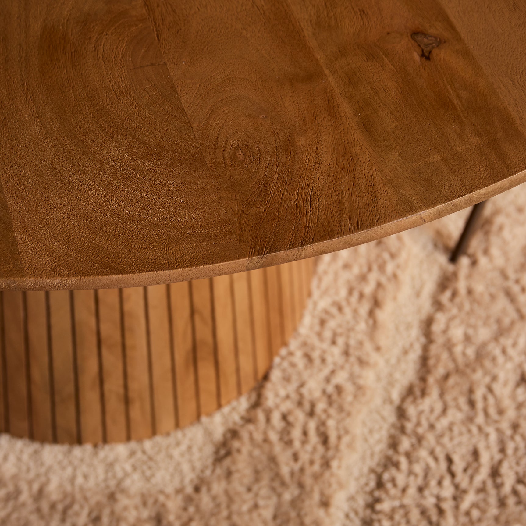Detail van naturel houten tafelrand en verticale ribben van de centrale sokkel