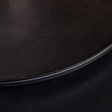 Zwart tafelblad-detail met afgeronde rand en donker onderstel.