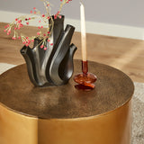 Gouden ronde salontafel Fiore met zwart metalen organisch stuk en staande kaars.