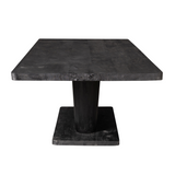 Zwarte eettafel met groot rechthoekig blad en massieve centrale poot.