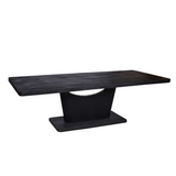 Zwarte eettafel met langwerpig blad en brede centrale poot op voetstuk.