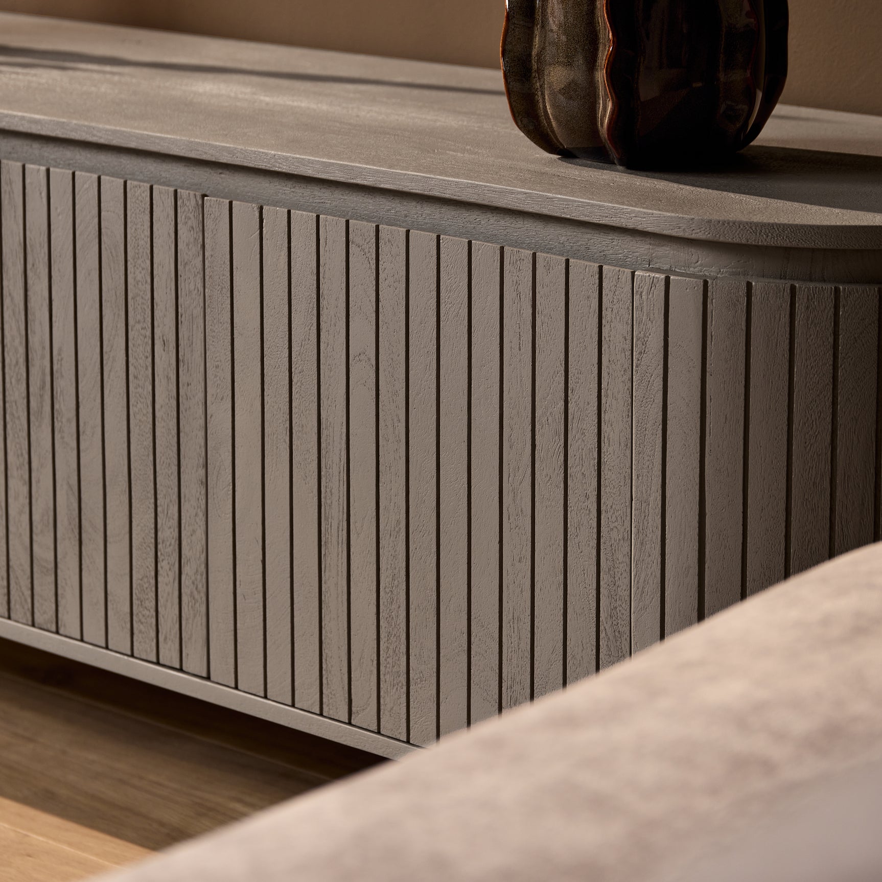 Tv-meubel zijpaneel met verticale ribbels en taupe/grijze afwerking.