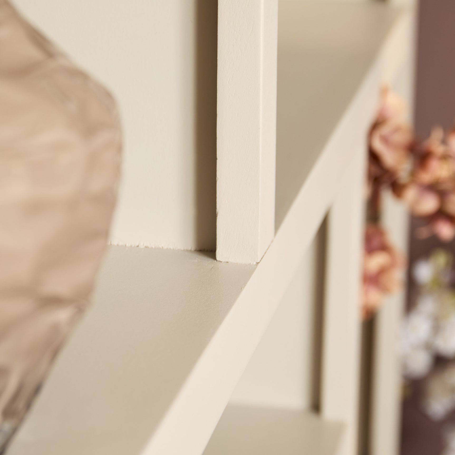 Detail onderin van witte vakkenkast met open schap