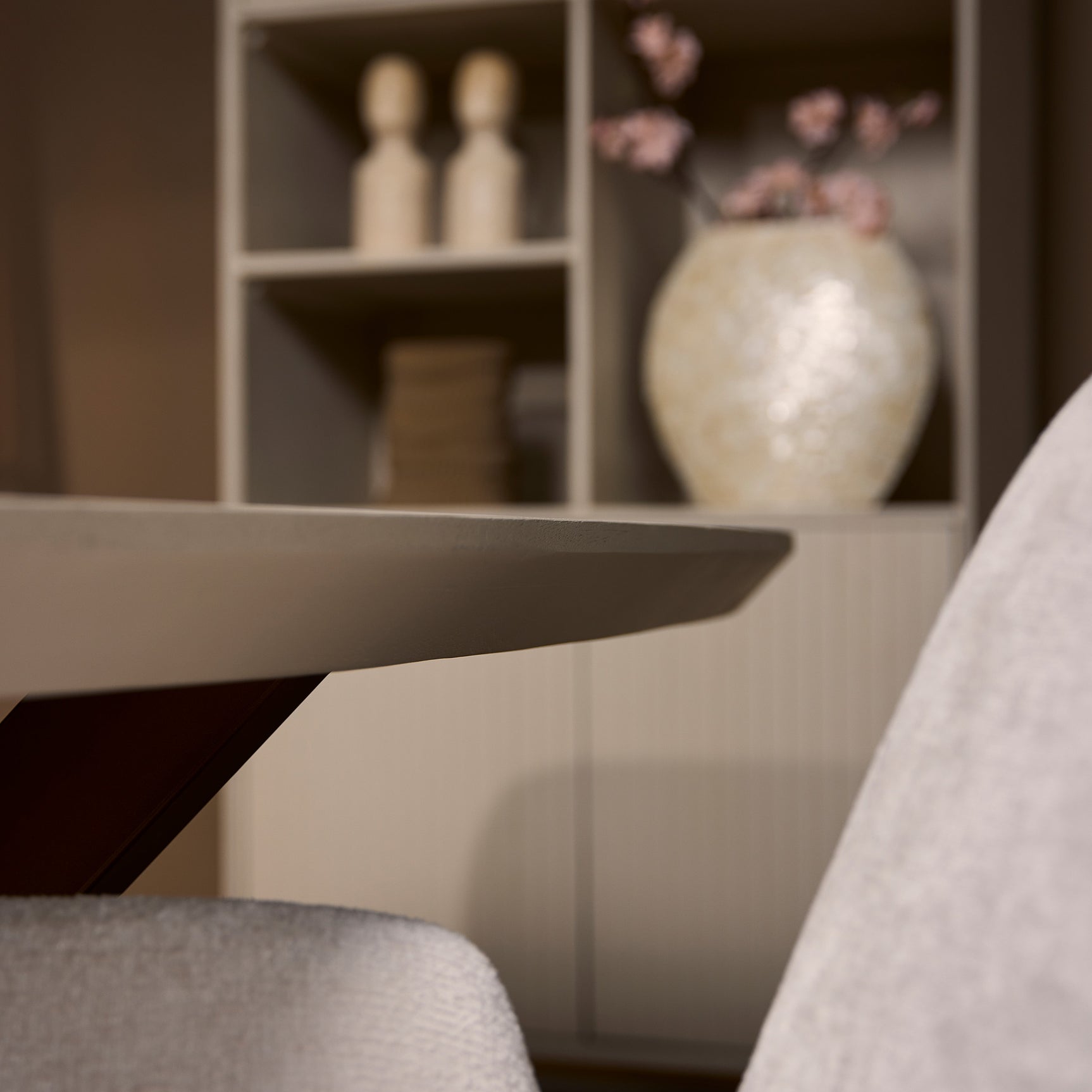 Ovale eettafel met zandkleurig blad en donkere kruispoten, detail op pootconstructie