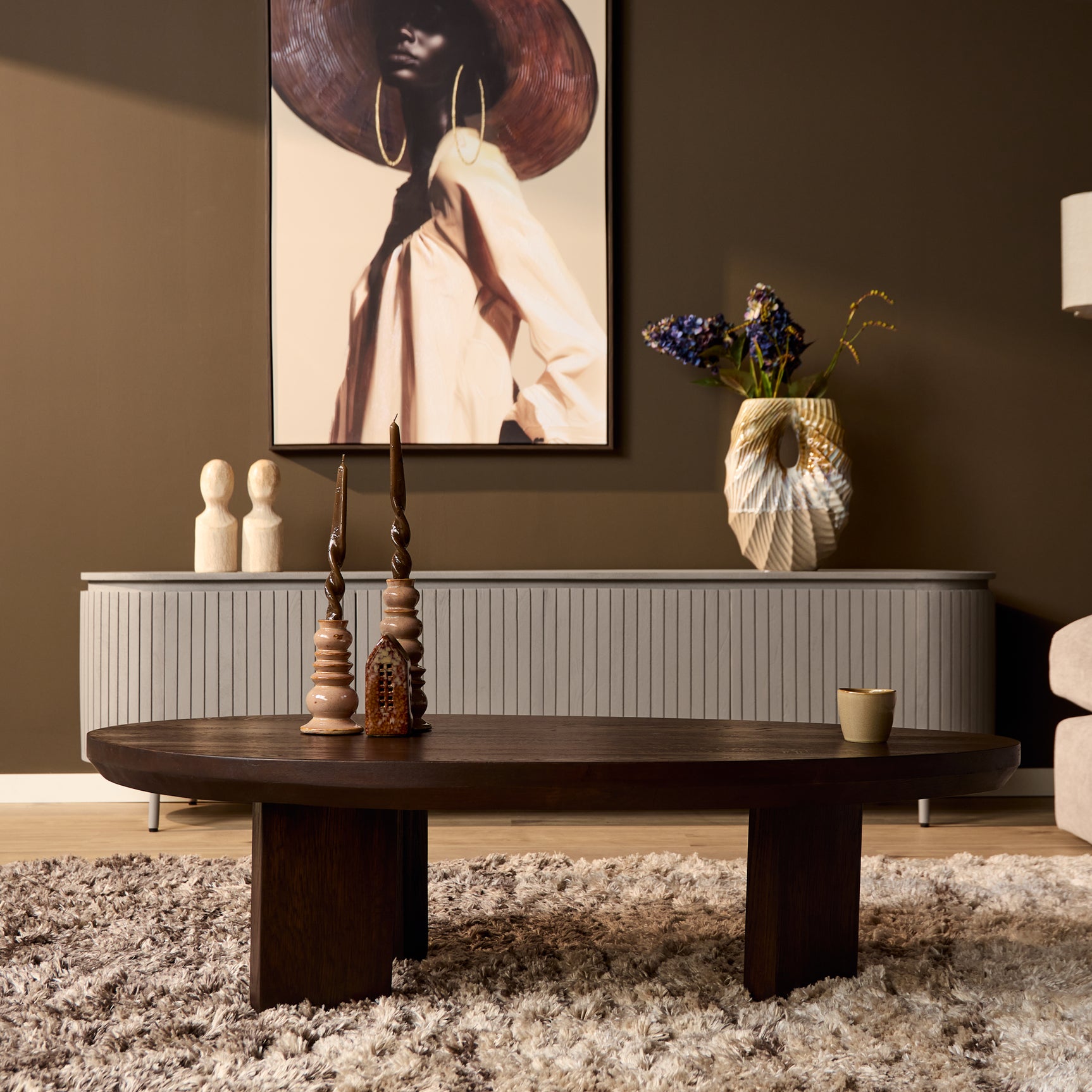 Donkerbruine ronde eikenhouten salontafel met vier korte poten en decor op blad