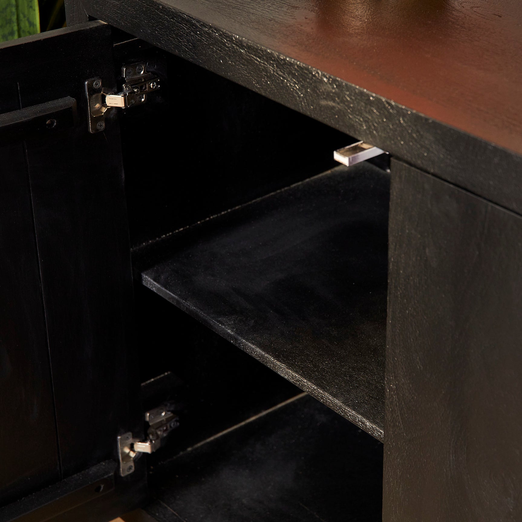 Zwart dressoir met open lade, metalen scharnieren en binnenvak zichtbaar.