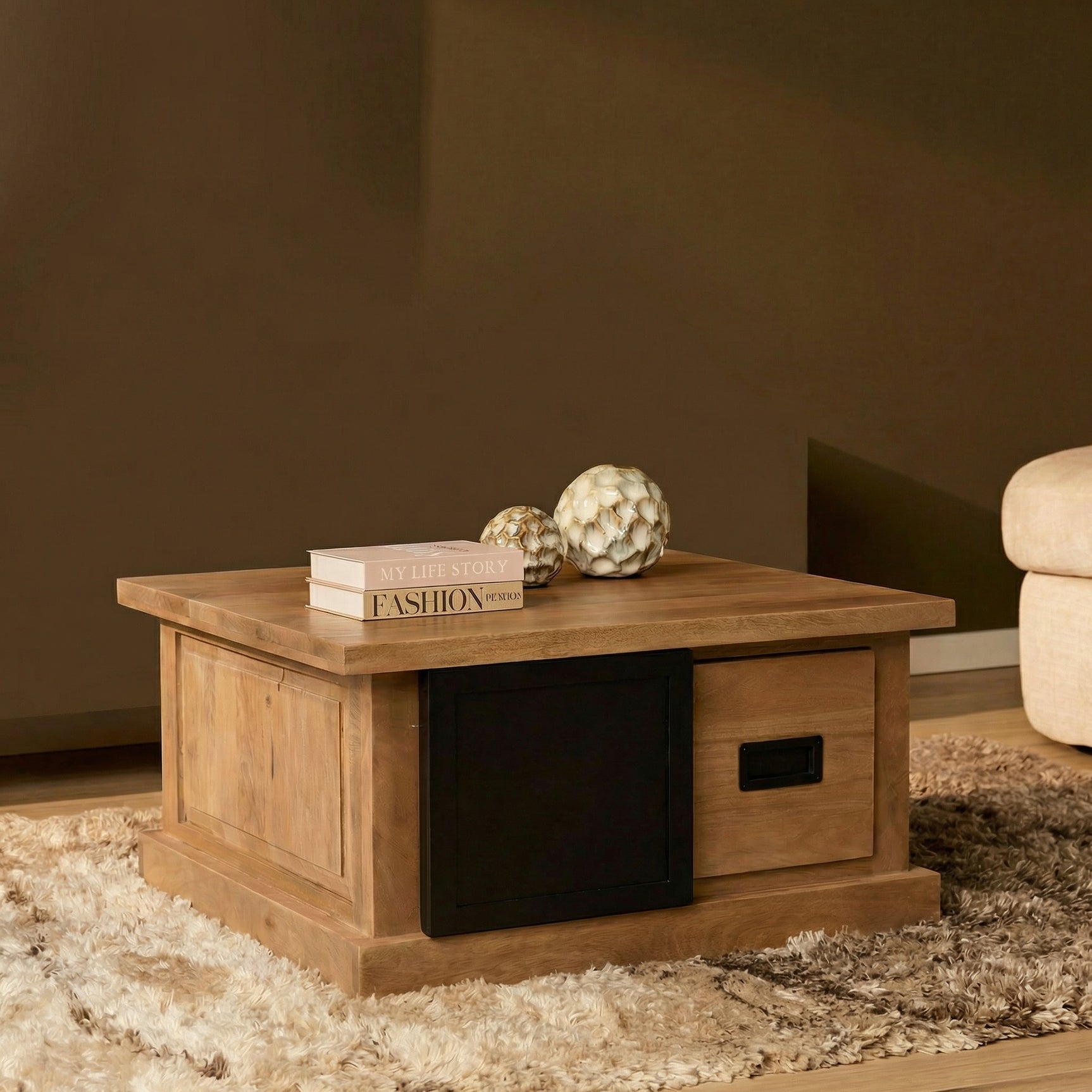 Salontafel met houtkleurige kast en zwarte ladefront, met blad en decoratie bovenop.