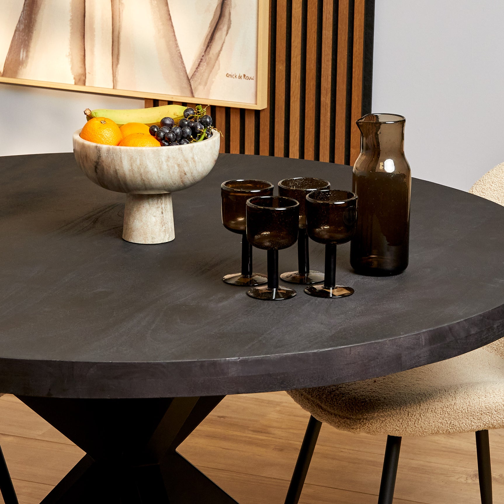 Ronde eettafel met donker blad en zwart X-onderstel, met servies en vaas