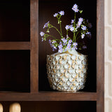 Open vak in bruine vakkenkast met vaas en bloemen op een houten plank.