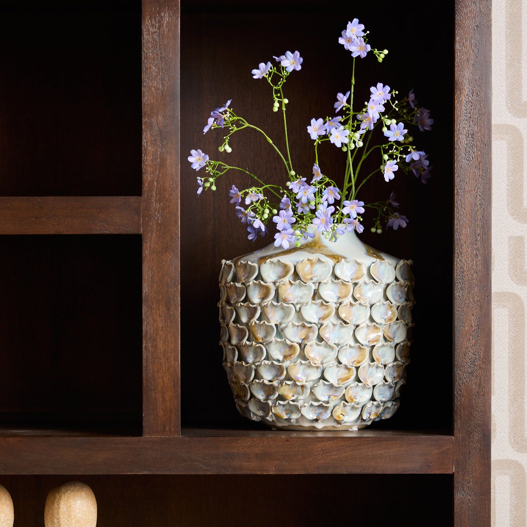Open vak in bruine vakkenkast met vaas en bloemen op een houten plank.