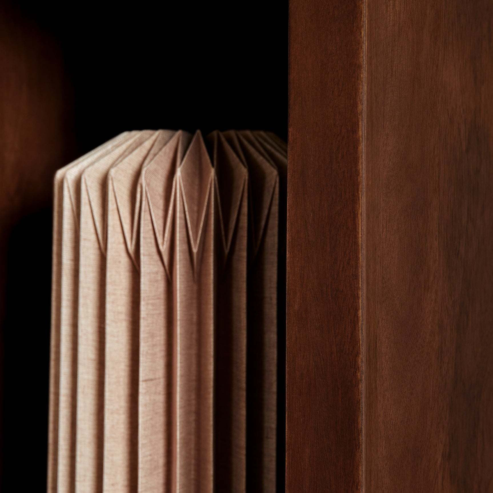 Open vak in bruine vakkenkast met opgevouwen beige textiel.