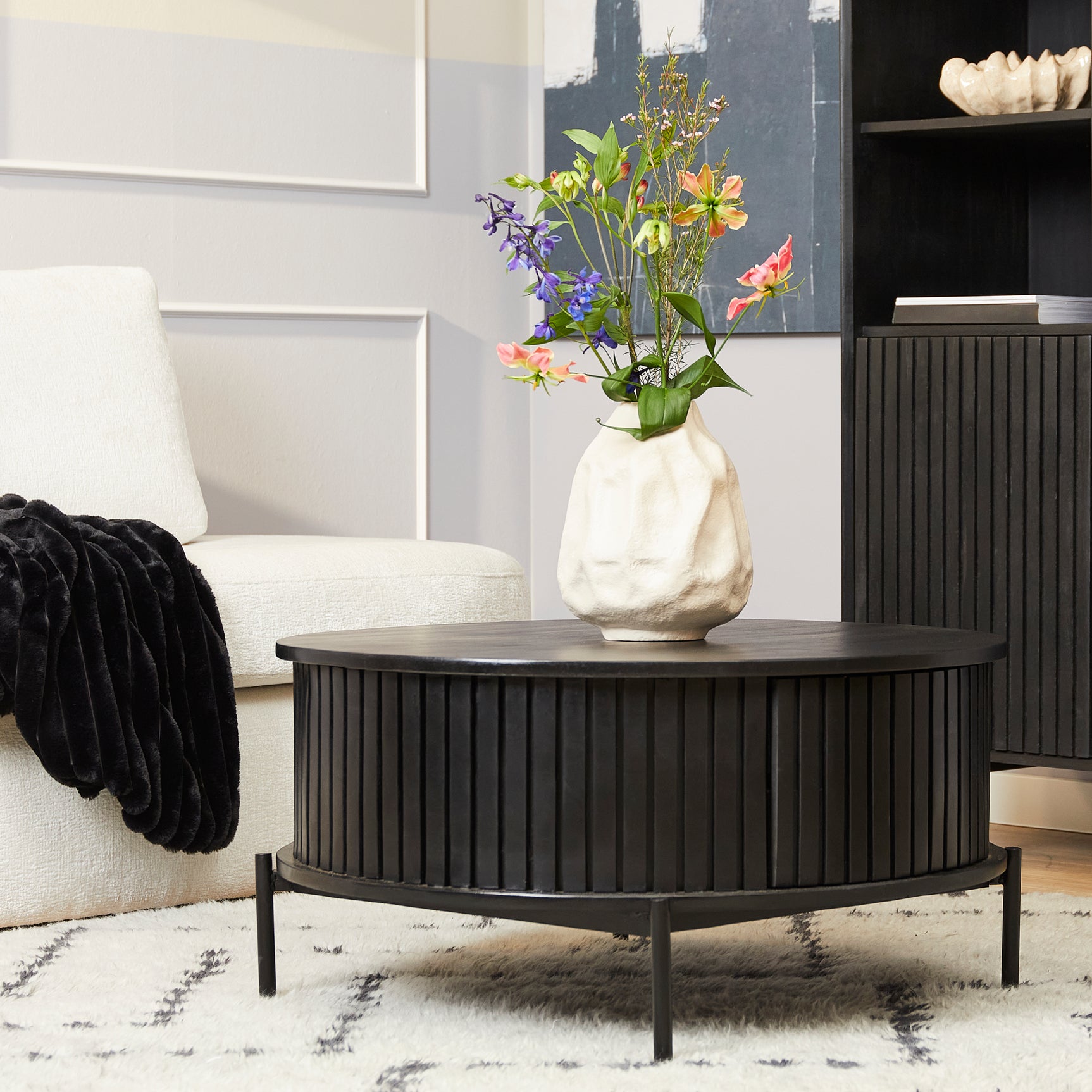 Ronde salontafel met zwarte, geribbelde zijkant en zwart blad op smalle pootjes