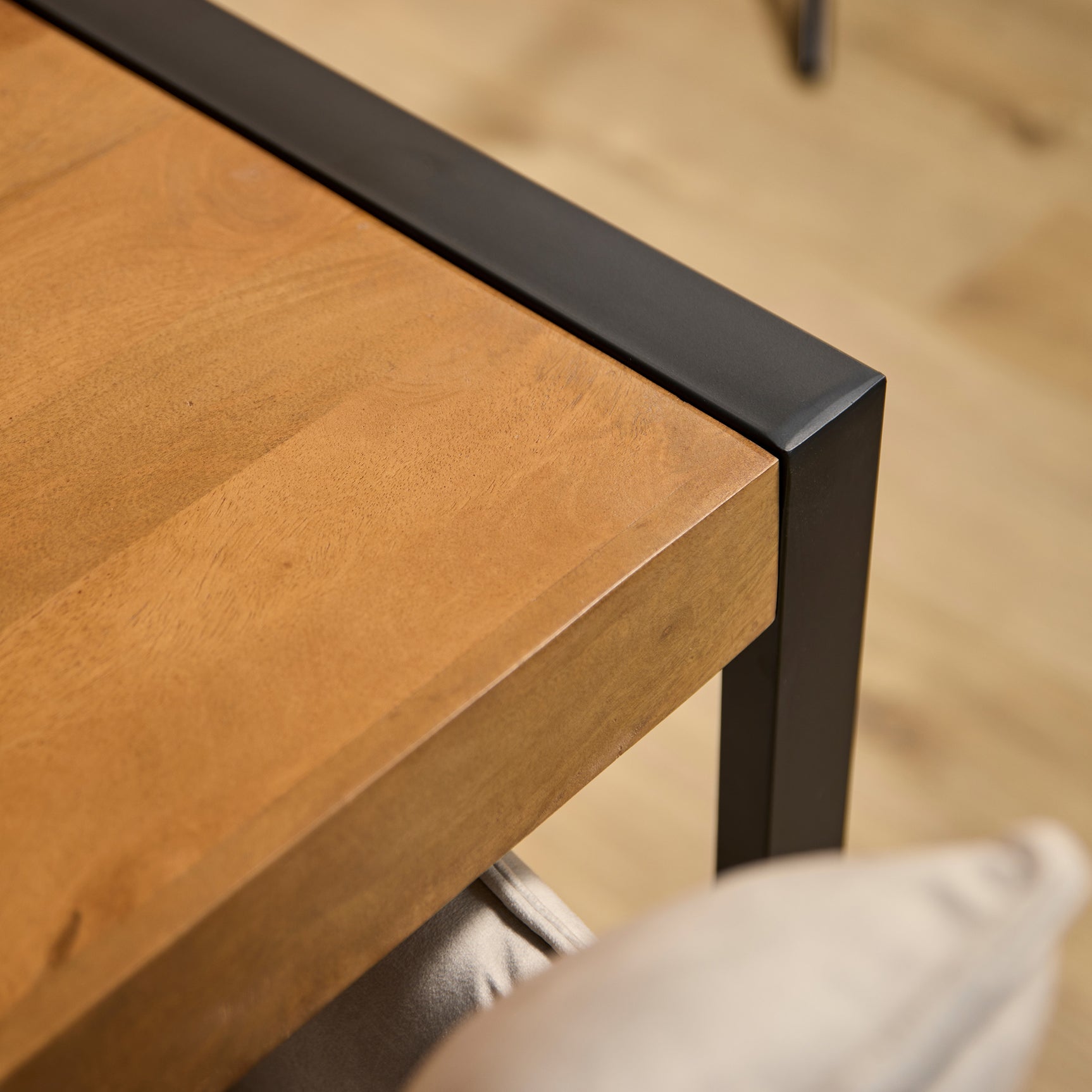 Eettafel met houtnerf blad en zwarte metalen rand, close-up van hoek en zijkant