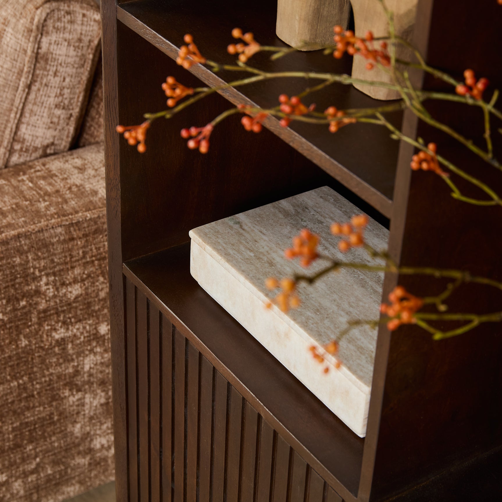 Bruine open vakkenkast met schap in een lagere houder en verticale groeven aan de zijkant.