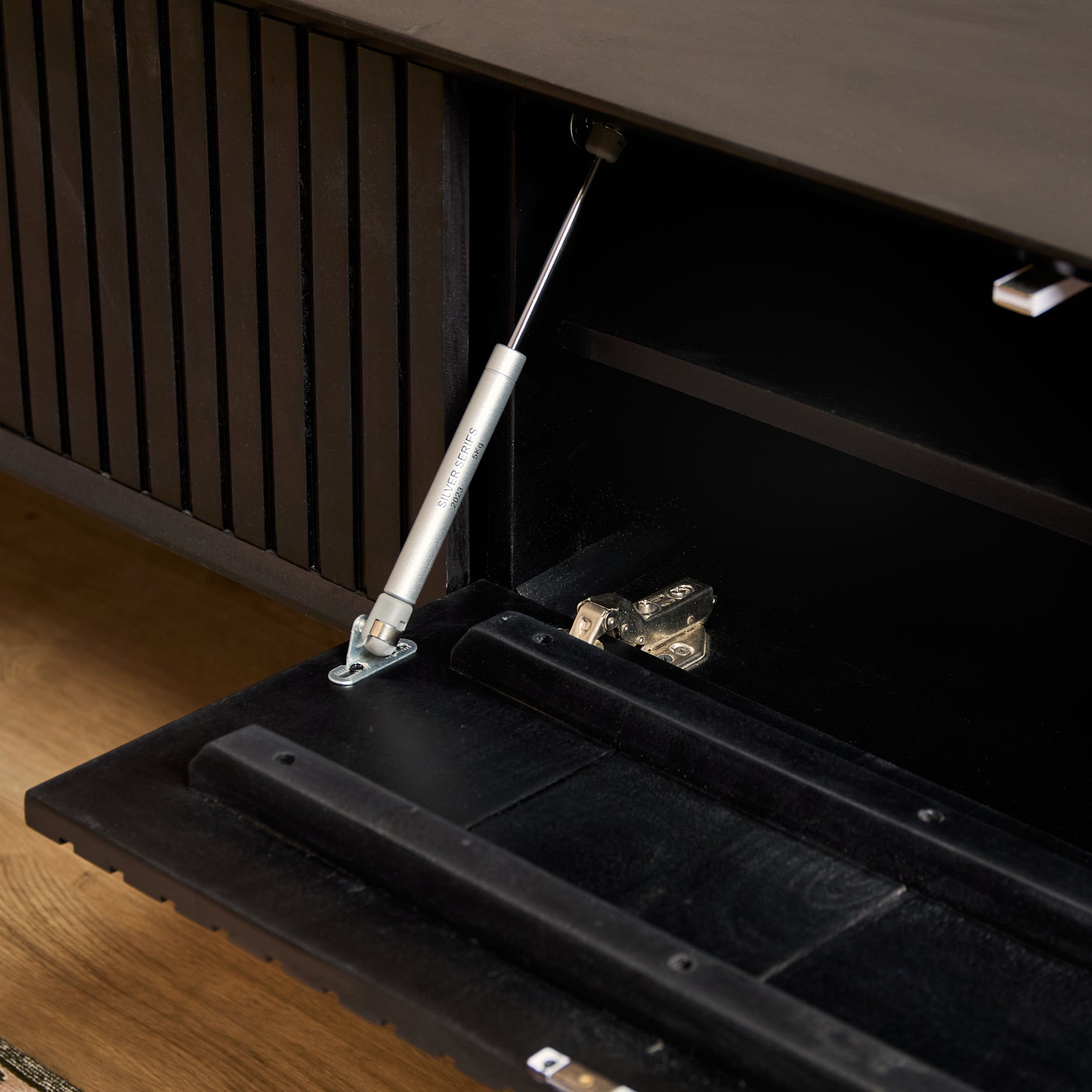 Zwart zwevend tv-meubel met open kabelruimte en opbergplanken onder het blad