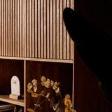 Vakkenkast-detail met open middenvakken en houtnerf; boek en decoratie in de vakken