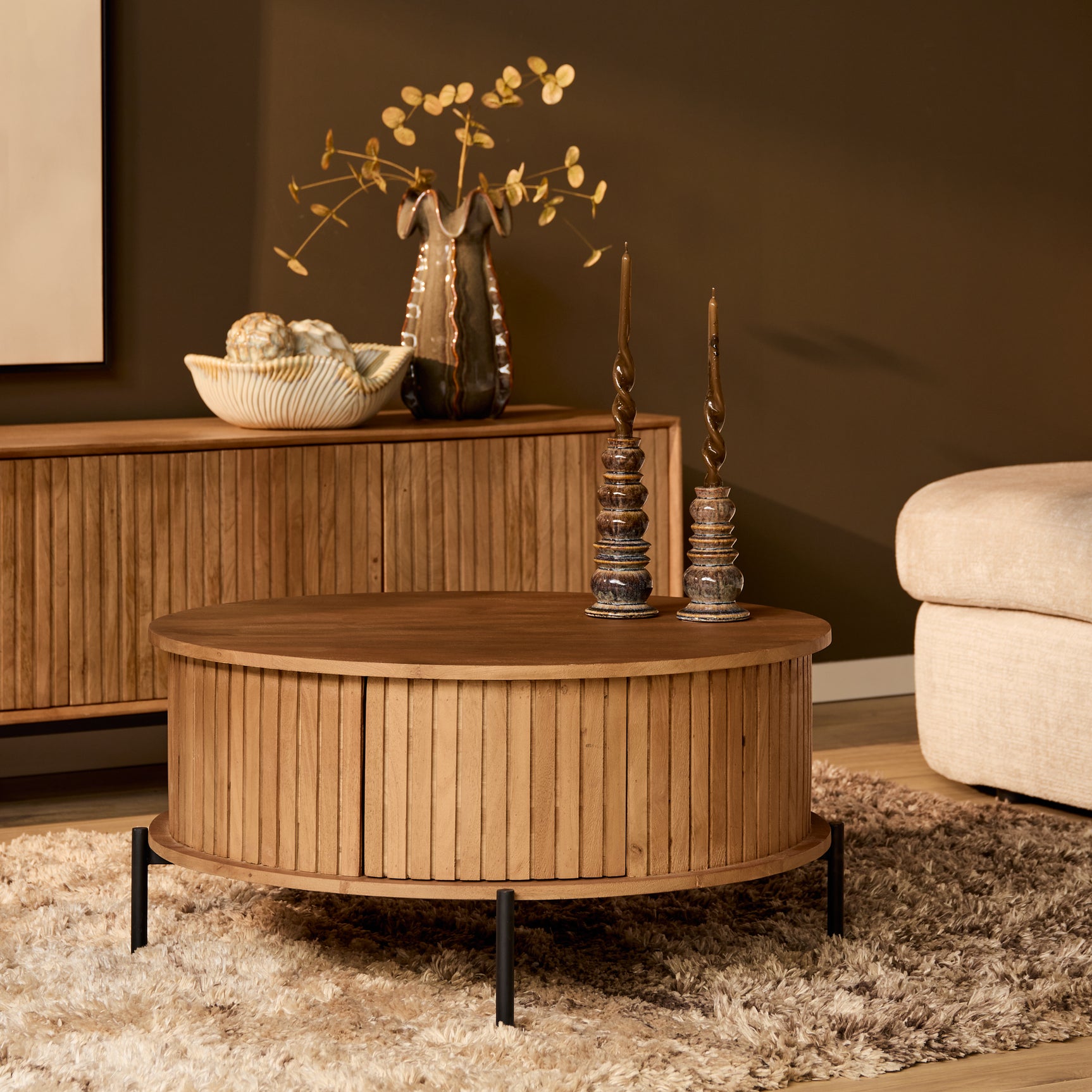 Ronde houten salontafel met ribbenfront en zwart onderstel, naturel blad.