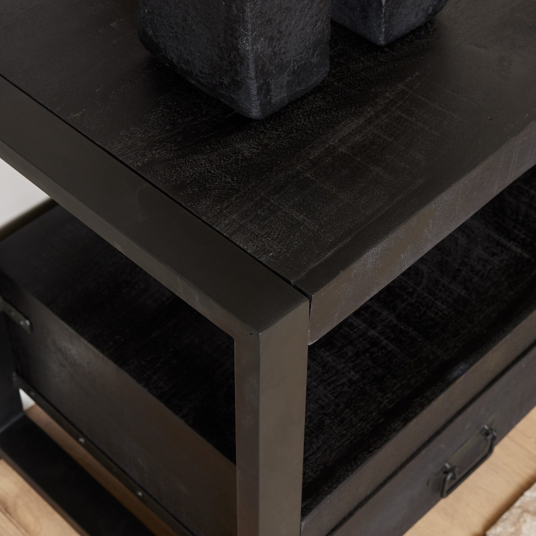 Zwart tv-meubel blad en rand, hoekdetail met verweerde houtstructuur