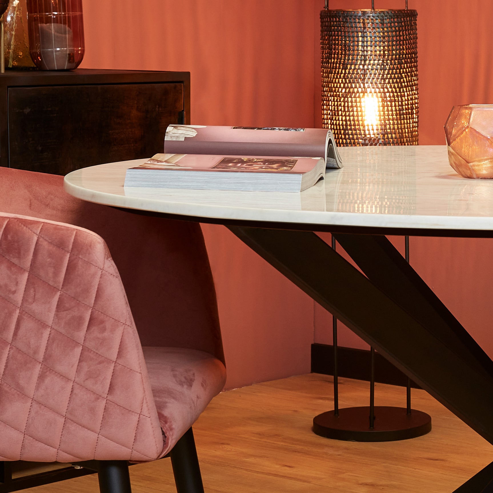 Ronde eettafel met wit marmeren blad en zwart diagonaal pootonderstel.