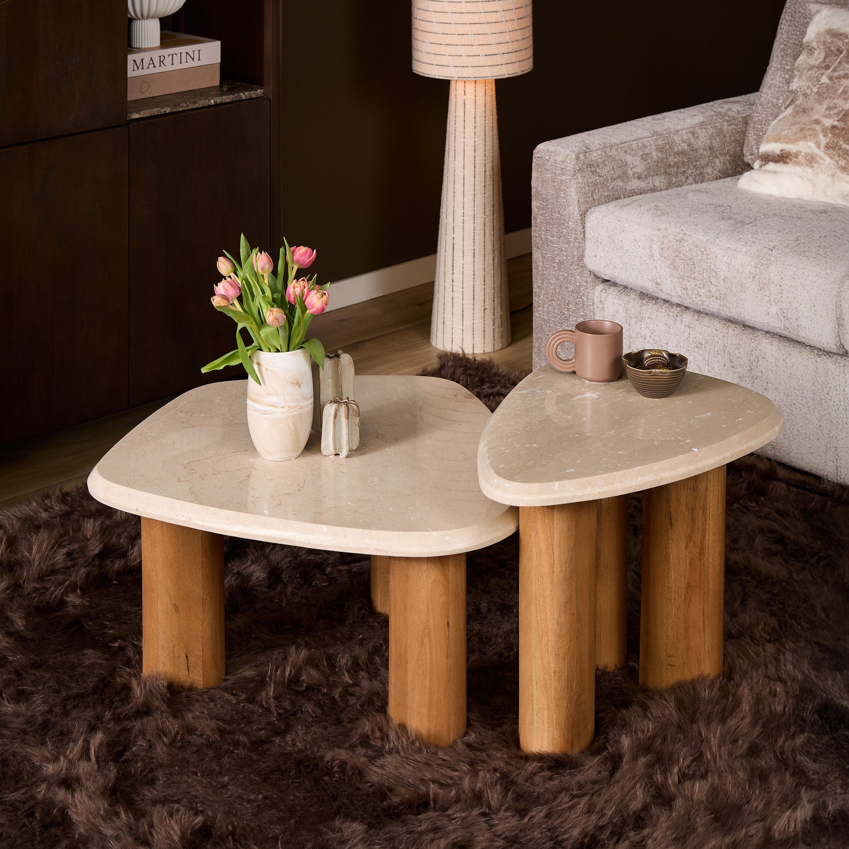 Twee ronde bijzettafels met lichtbeige bladen en houten, cilindrische poten.