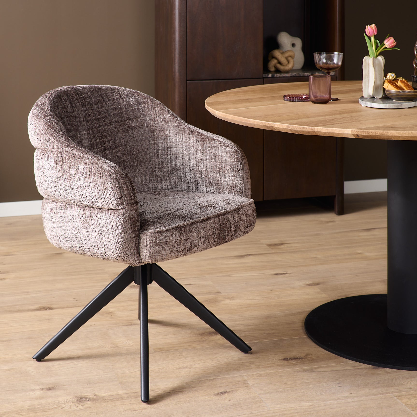 Eetkamerstoel met armleuningen, beige stoffering en zwarte draaipoot, schuin