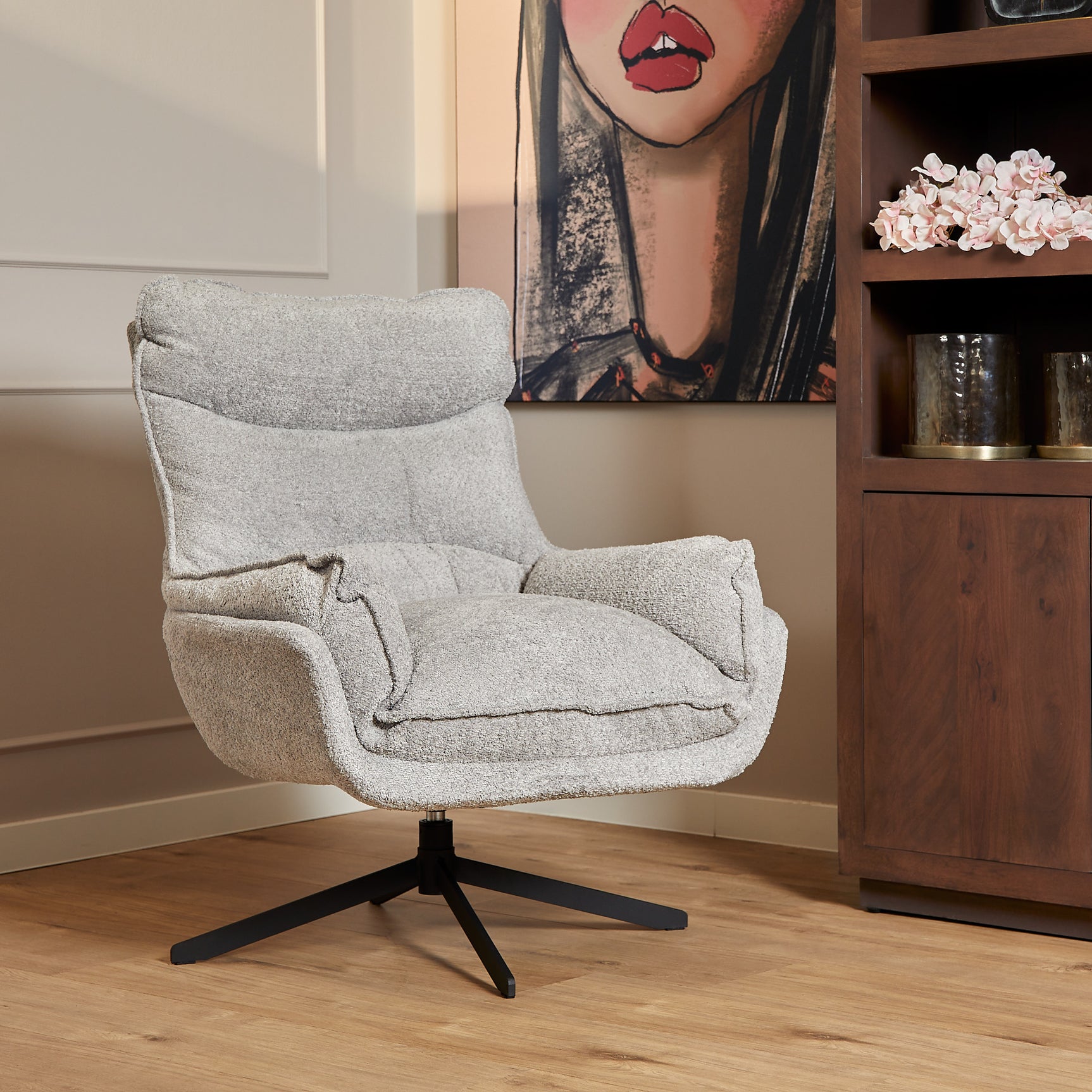Lichtgrijze Fauteuil Vera met brede armleuningen, ronde rug en zwarte draaivoet.