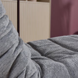 Grijze relaxfauteuil met geplooide arm en zitting op stoffen oppervlak