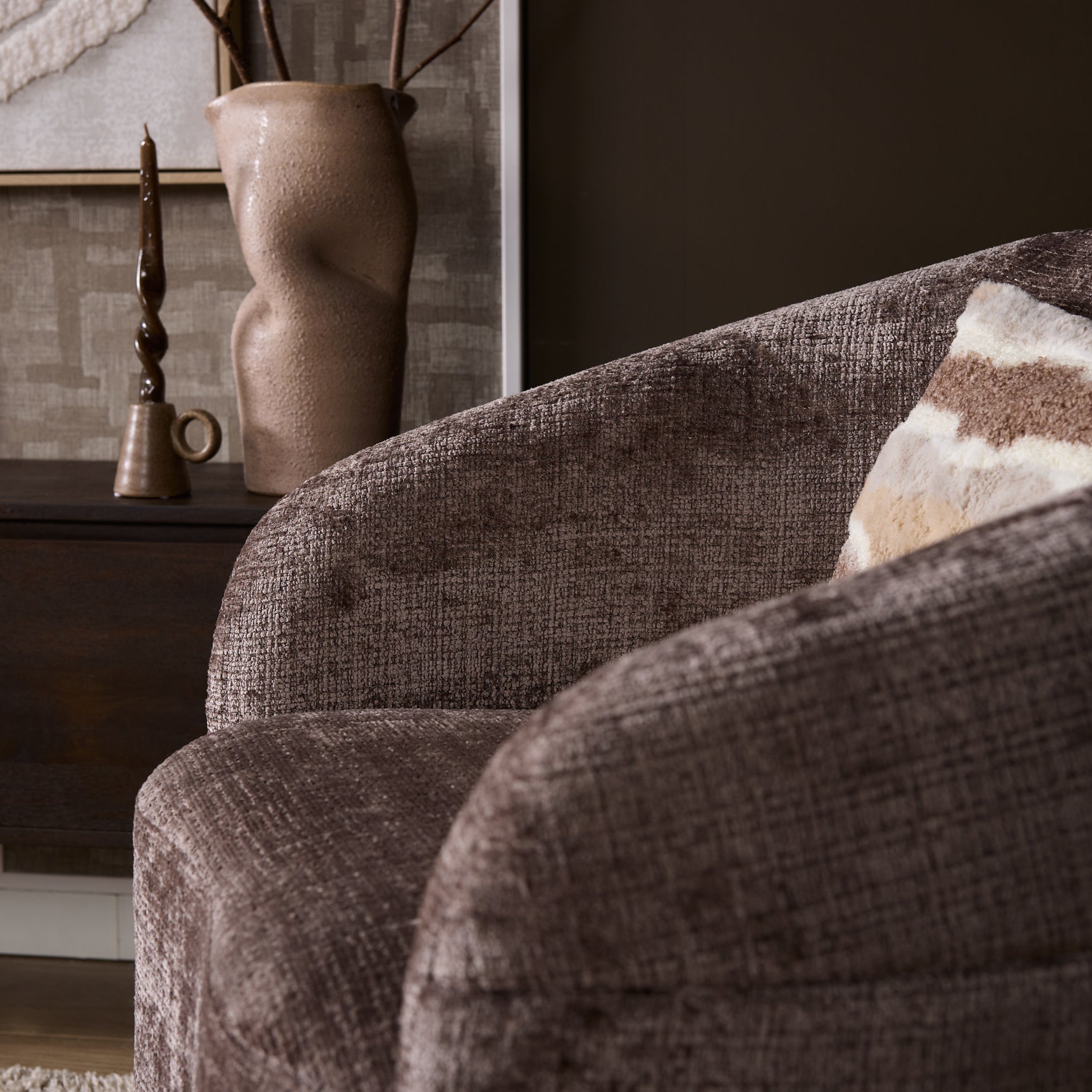 Fauteuil Yara met beige stoffering, close-up van afgeronde arm en gestoffeerde rug