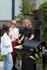 Zwarte elektrische barbecue met open deksel en gegrilde etenswaren op het rooster